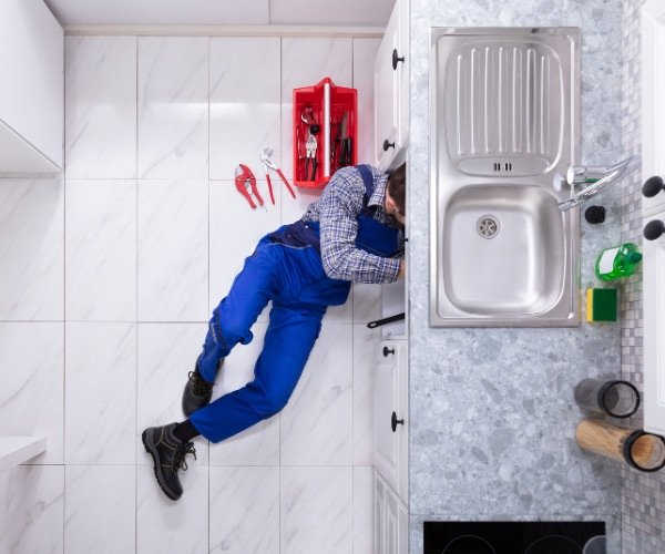 Plombier travaillant sous l'évier d'une cuisine